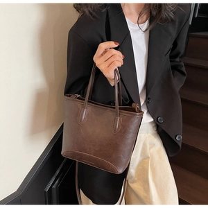 Detail of vintage dark brown faux leather tote with dual handles and smooth texture