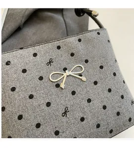 Detail of grey polka dot fabric with embroidered bows and a silver metal bow clasp