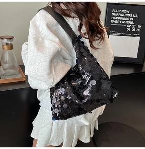 Detail of black sequin tote bag featuring large reflective discs and a fashion brand label