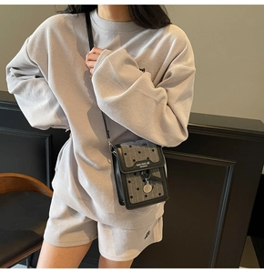 Détail du mini sac à rabat rétro noir et gris sur tenue en tissu gaufré gris clair