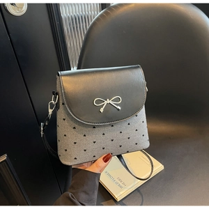 Détail du sac bandoulière à imprimé cœur avec une boucle en forme de nœud argenté