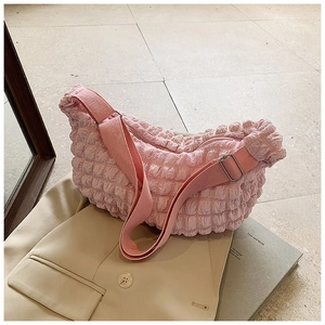 Detail of pink bubble textured crossbody bag with soft pleated fabric on beige suit