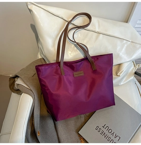 Detail of purple nylon tote bag with brown leather handles and a stylish fashion label