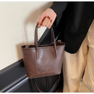 Detailed view of the dark brown retro leather texture and embossed text on the tote bag base