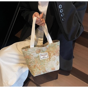 Detail of vintage floral jacquard tote bag with textured woven handle and fabric patch