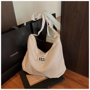 Dettaglio borsa hobo in nylon bianco con coulisse a righe e etichetta Fashion su legno