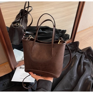 Detailed macro view of dark brown faux leather tote with vintage cracked texture and gold hooks