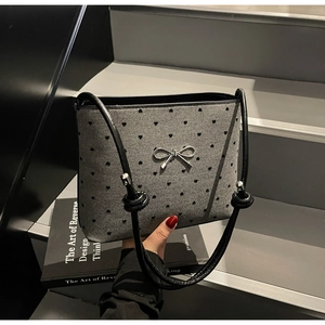 Detail of grey canvas handbag with black heart pattern and silver metal bow ornament