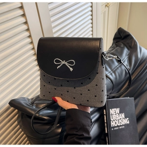 Détail du sac gris à motif cœur avec rabat noir et ornement nœud en métal argenté