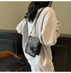 Vue détaillée du mini sac bandoulière gris à pois avec sangle en cuir et breloque dorée