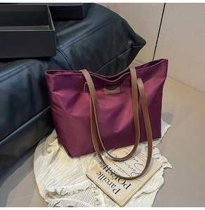 Close-up of purple nylon tote bag featuring leather handles and a fashion logo patch