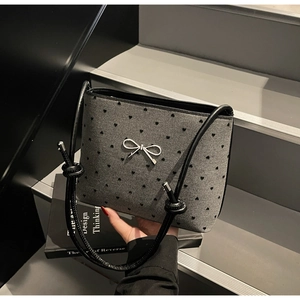 Detail of grey canvas tote bag with black heart embroidery and white ribbon bow