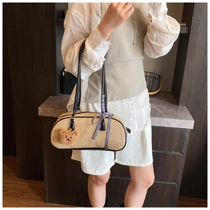 Detail of summer woven handbag featuring a blue plaid bow and cute plush bear charm