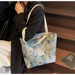Detail of floral jacquard tote bag with cream webbing straps on dark wooden stairs
