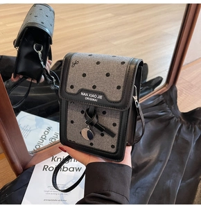 Détail d'un sac à téléphone rétro en laine grise à pois avec nœud en cuir noir