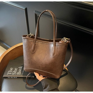 Detailed macro view of vintage brown oil-wax PU leather texture and gold hardware on tote bag