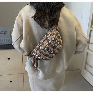 Detail of vintage geometric woven chest bag with colorful patterns and braided zipper pulls