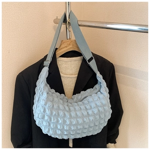 Detailed view of the light blue bubble textured fabric and adjustable strap of hobo bag