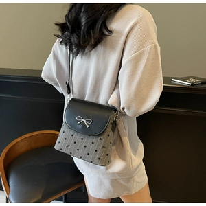 Sac bandoulière à pois avec nœud argenté et rabat en cuir porté par un mannequin