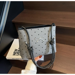 Close-up of grey textured fabric tote bag with black heart patterns and silver bow buckle