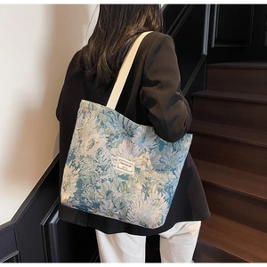Detail of floral jacquard tote bag with beige cotton shoulder straps and brand label
