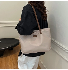 Detailed view of a large beige tote bag with brown leather straps and fashion label detail