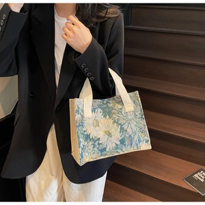 Close-up of floral tapestry tote bag with canvas side panels and white fabric handles