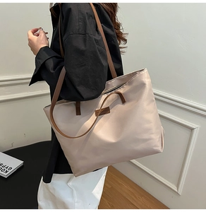 Close-up of large beige nylon tote bag with brown faux leather straps for daily commute