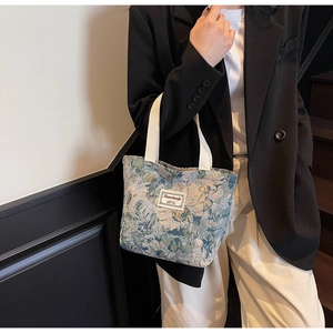 Detail of teal floral brocade canvas tote bag with white woven handles and label