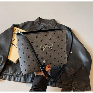 Detail of grey wool shoulder bag featuring black polka dots and silver metal bow clasp