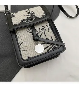 Close-up of beige canvas crossbody bag with black floral print and leather trim detail