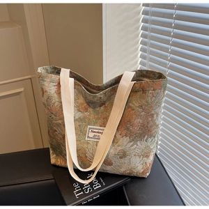 Detail of vintage floral jacquard tote bag with cream canvas straps on leather surface