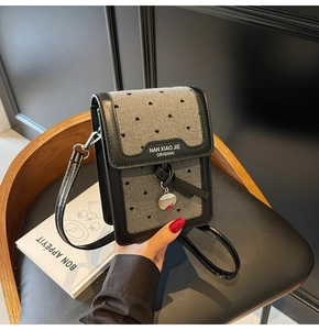 Détail du sac de téléphone en denim gris à cœurs, rabat noir et pendentif argenté