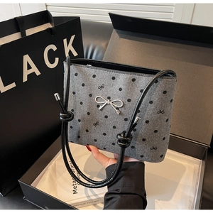 Detailed view of grey polka dot canvas bag with silver bow buckle and knot strap detail