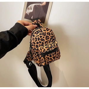 Close-up of leopard print mini backpack showing zip compartments and adjustable strap