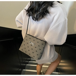 Close-up of grey canvas crossbody bag with black bow prints and silver bow metal detail