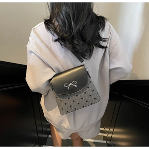 Detail of trendy bow-knot crossbody bag showing metallic buckle and grey polka dot texture