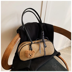 Close-up of woven cylinder bag with ribbon bow and plush bear charm on a vintage chair
