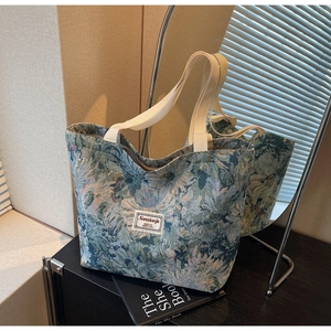 Detail of vintage floral jacquard tote bag with textured fabric and woven logo tag