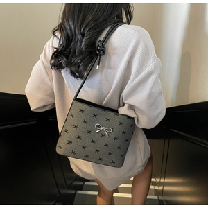 Detail of grey bucket bag featuring black mini bow prints and a silver bow clasp