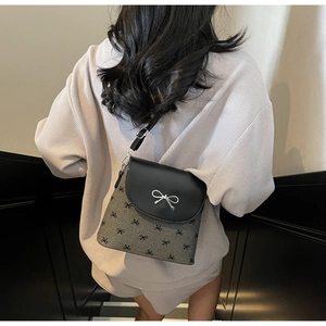 Sac seau bandoulière tendance à motifs de nœuds porté par un mannequin en décor épuré