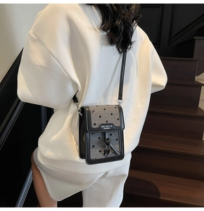 Sac bandoulière en tissu à pois et cuir porté par un mannequin sur des escaliers