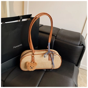 Detail of woven straw handbag with brown leather handles and a cute bear charm