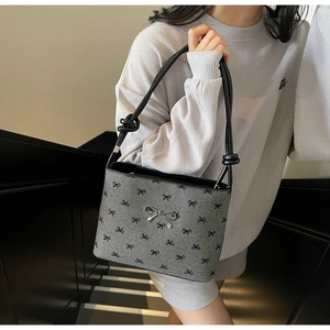 Detailed view of grey canvas bag with black bow patterns and silver metal bow clasp