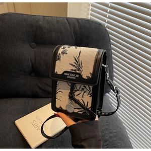 Close-up of beige linen crossbody bag with black plant pattern and leather trim