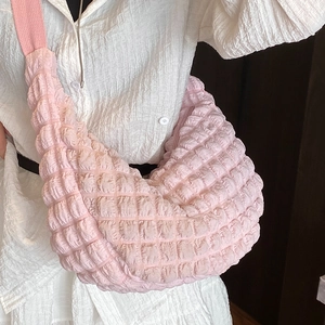 Pink crescent cloud bag with popcorn texture and wide strap shown on a model