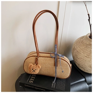 Close-up of woven straw bag texture with brown leather handles and cute bear charm
