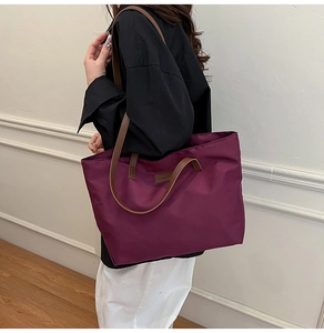 Detail of plum large capacity tote bag with brown leather handles and nylon fabric