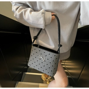 Detail of grey polka dot canvas bag with silver bow ornament and black leather handles
