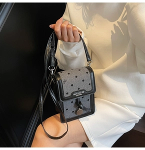 Détail du tissu à pois gris et des garnitures en cuir noir sur un mini sac pour téléphone